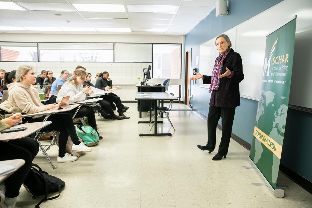 Professor teaching a classroom with the Schar School banner