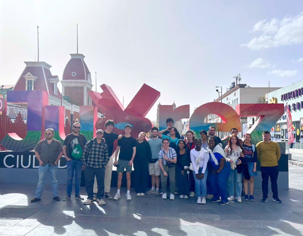 group of students stand in front of the cuidad juarez sign